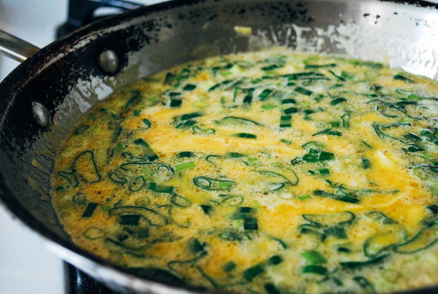 Slow-cooked scrambled eggs require patience, but reward the eater with exceptional flavor. These slow-cooked scrambled eggs are mixed with ricotta, Parmesan, garlic scapes, and spring onions, but feel free to add whatever cheese and alliums you may have on hand. 