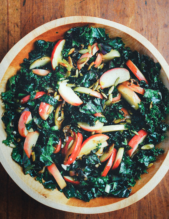 A bowl of kale salad on a wooden table.