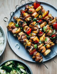 A platter of grilled chicken kebabs with pineapples and peppers.