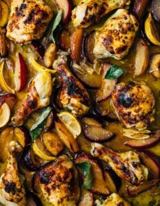 A roasting pan with saffron chicken and plums.