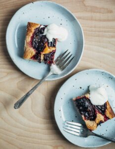 Two sliced of plum cake with whipped cream.