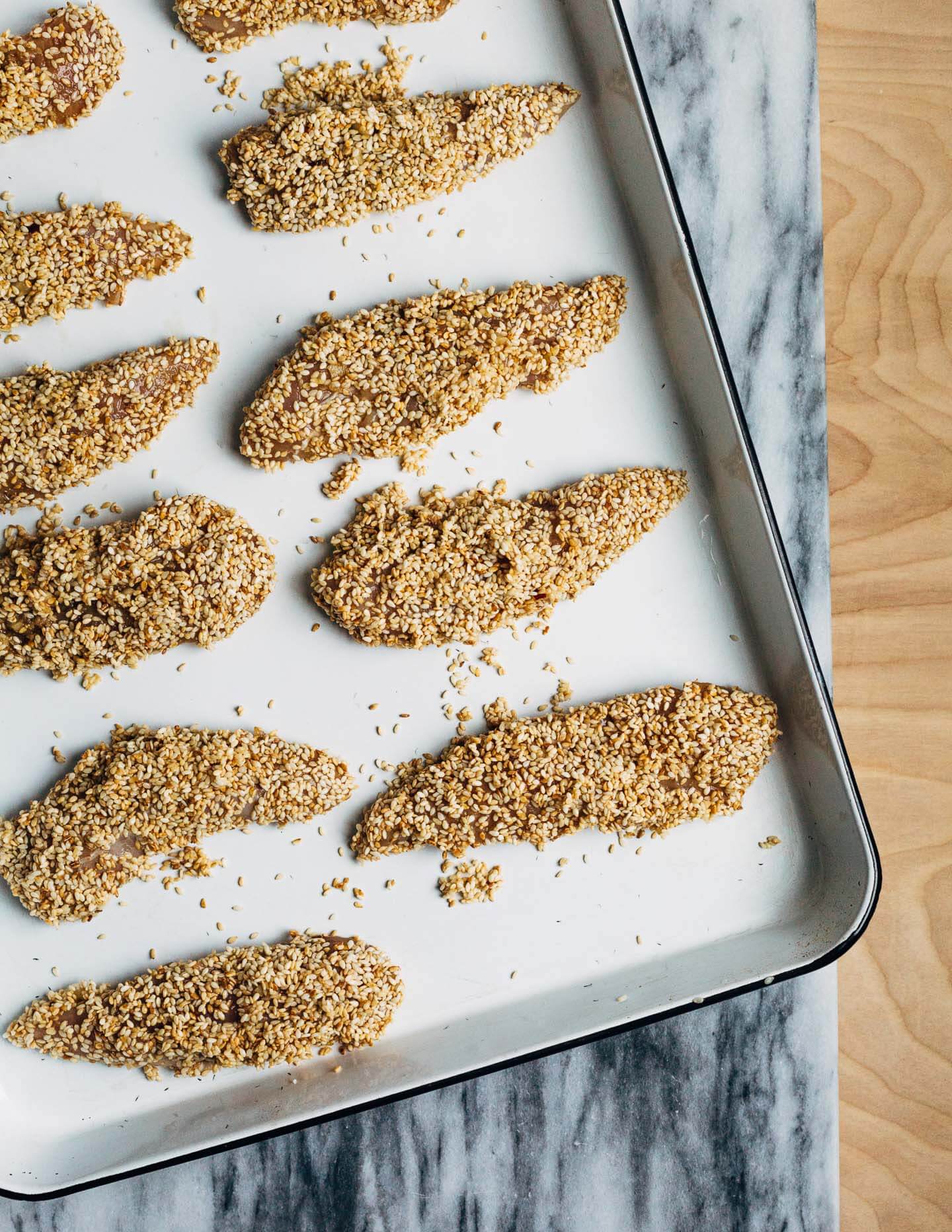 A healthful, Whole30-compliant avocado and mandarin orange salad topped with crisp sesame-crusted baked chicken tenders and drizzled with a creamy mandarin-ginger dressing.