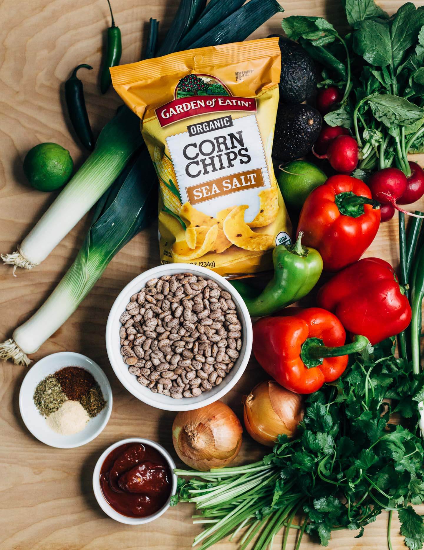 Hearty pinto bean chili with a flavorful tomato base flecked with leeks, chili peppers, and hominy and topped with fresh cilantro, lime, sliced avocado and radish, and crunchy corn chips. 