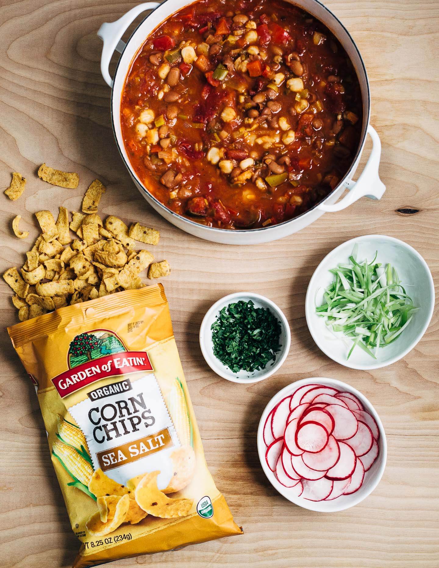 Hearty pinto bean chili with a flavorful tomato base flecked with leeks, chili peppers, and hominy and topped with fresh cilantro, lime, sliced avocado and radish, and crunchy corn chips. 