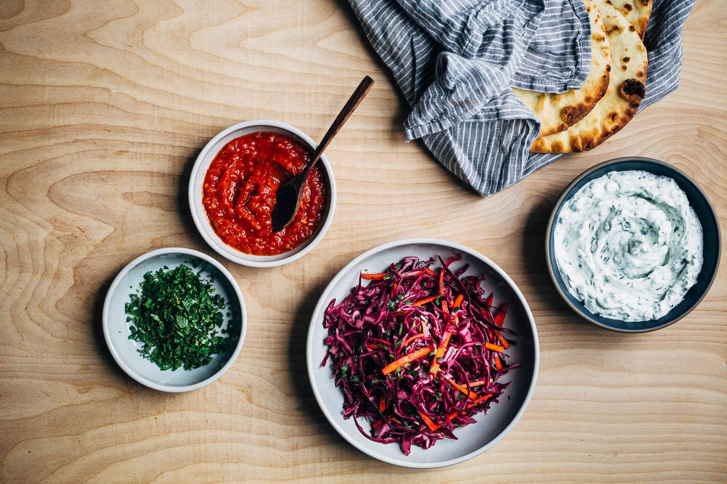 Exceptionally delicious merguez meatball flatbreads layered with red cabbage slaw, herbed yogurt, and harissa. 