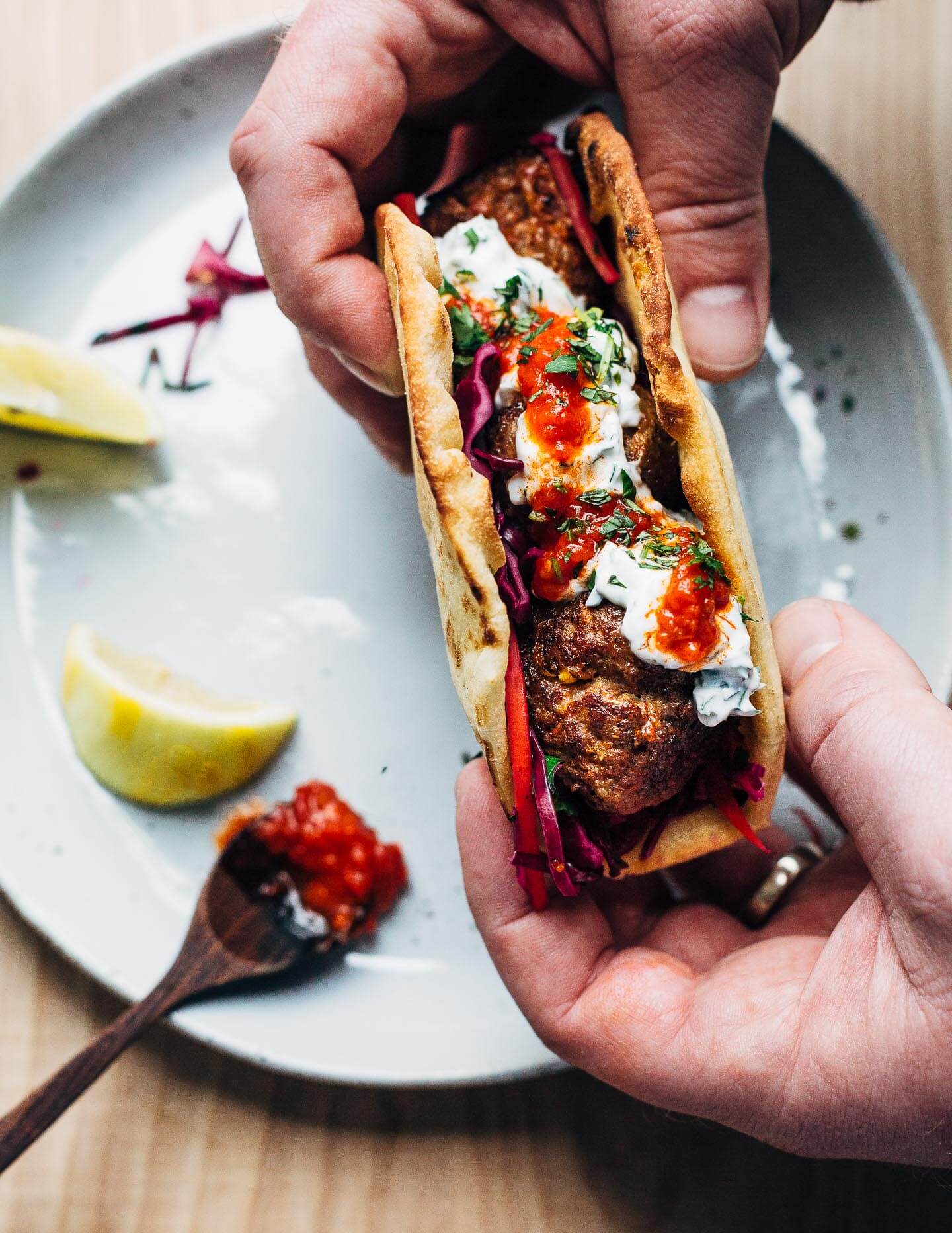 Exceptionally delicious merguez meatball flatbreads layered with red cabbage slaw, herbed yogurt, and harissa. 