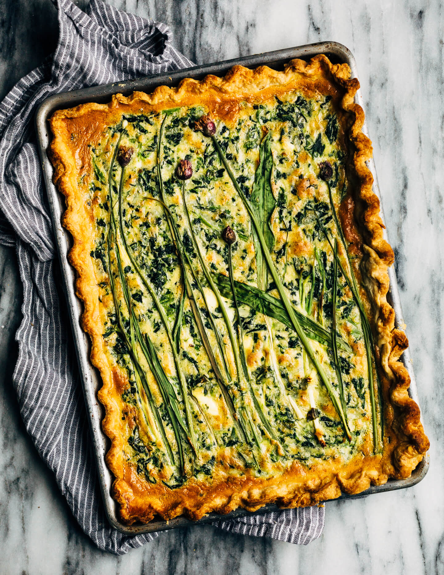Ideal for Mother's Day brunch or spring gatherings, this sheet pan spinach quiche, made with ramps, green garlic, and chives, is a delicious way to feed a crowd.