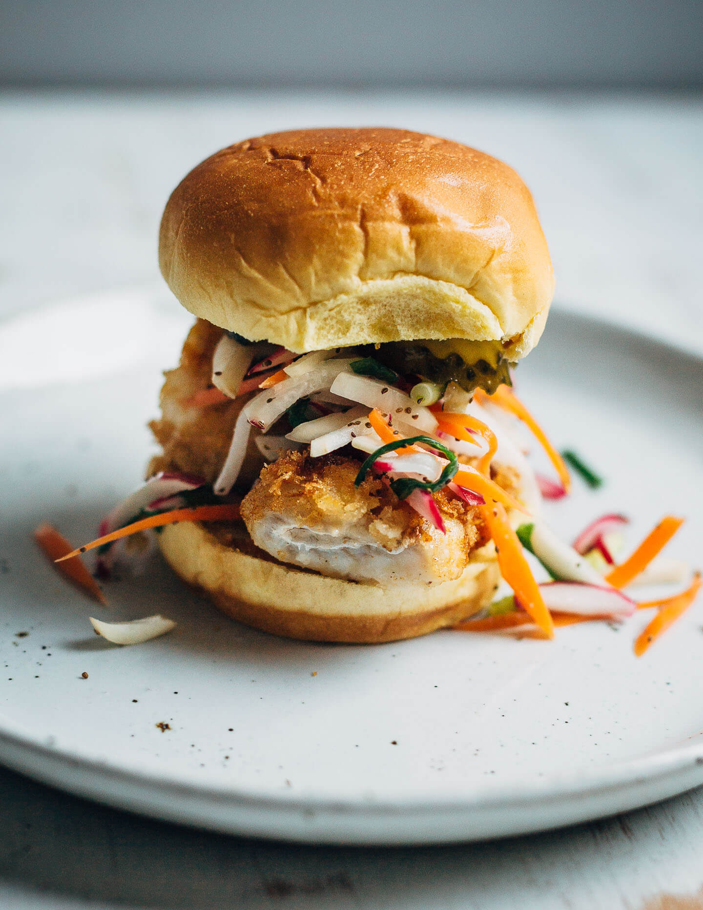 Panko-crusted fried fish sandwiches that are just right for a weeknight at home or a crowd-pleasing feast. Served with a simple radish slaw and bread and butter pickles, these flaky fish sandwiches hit all the right notes.
