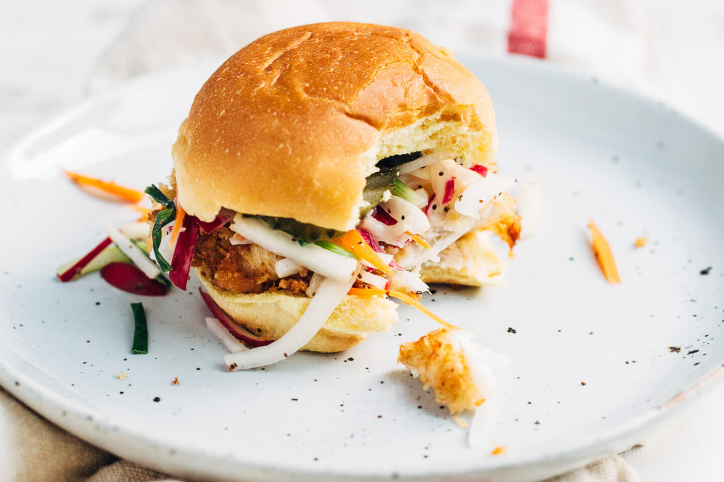 Panko-crusted fried fish sandwiches that are just right for a weeknight at home or a crowd-pleasing feast. Served with a simple radish slaw and bread and butter pickles, these flaky fish sandwiches hit all the right notes.