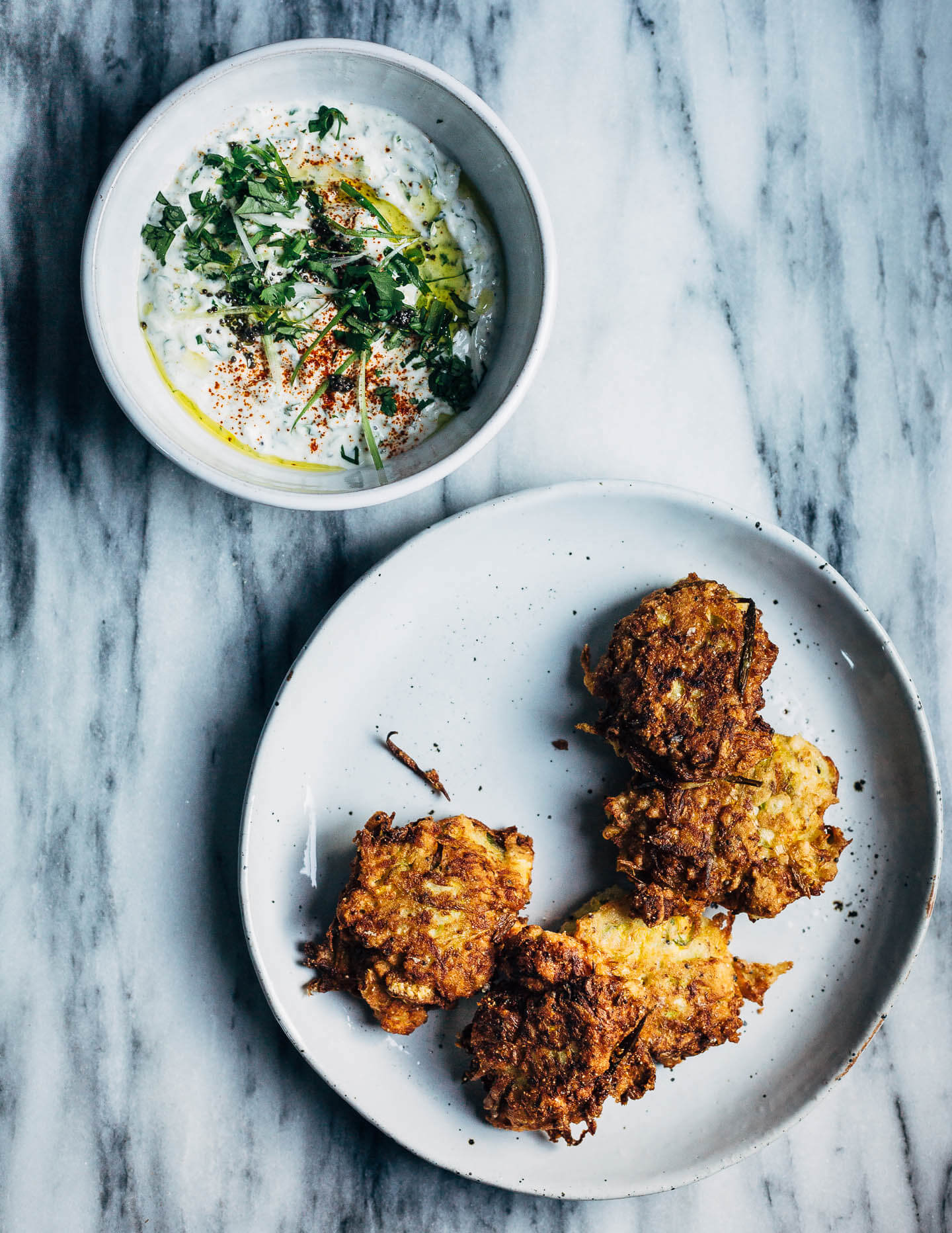 A plate of summer squash fritters alongside a dipping sauce. 