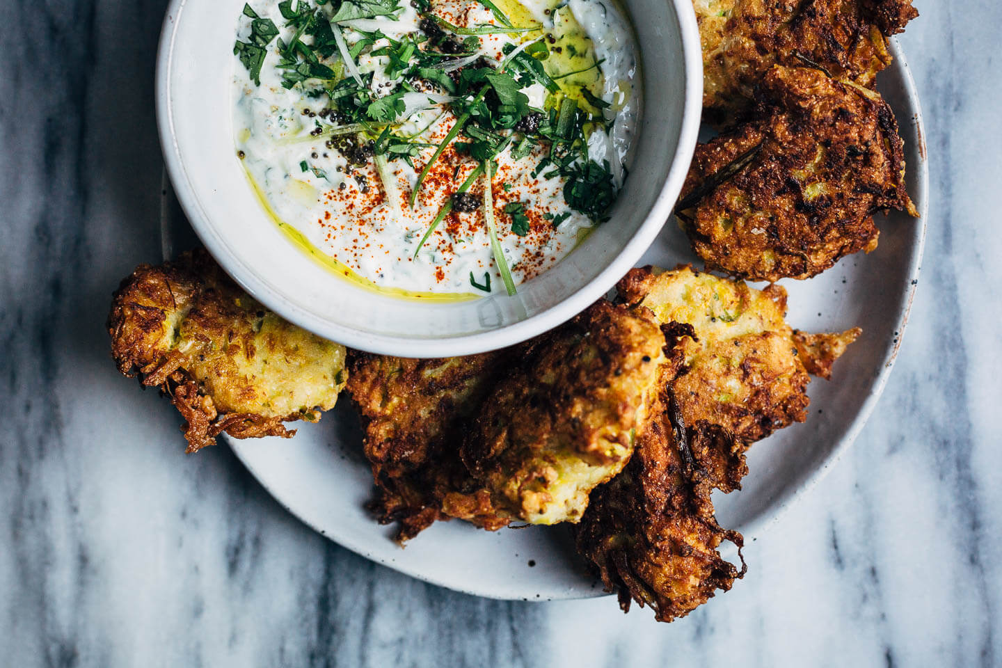 A plate of summer squash fritters alongside a dipping sauce. 