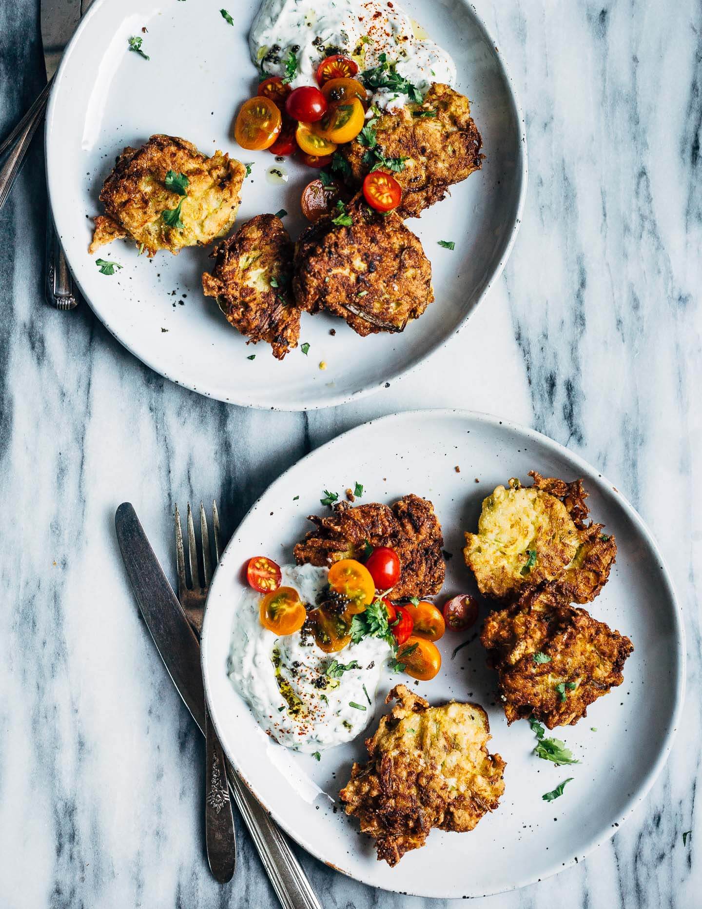 Plated fritters with raita and cherry tomatoes. 