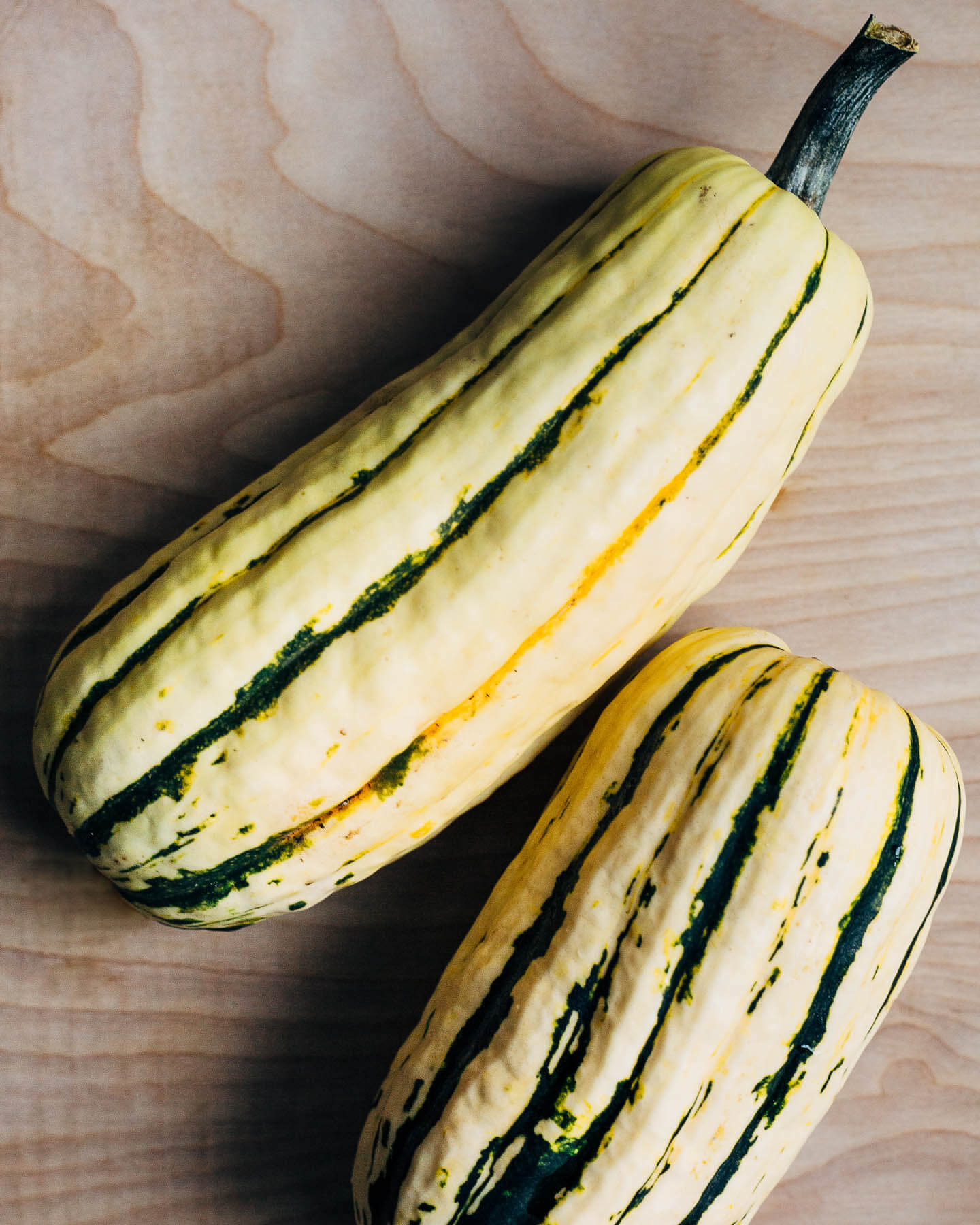Two delicata squash on a cutting board. 