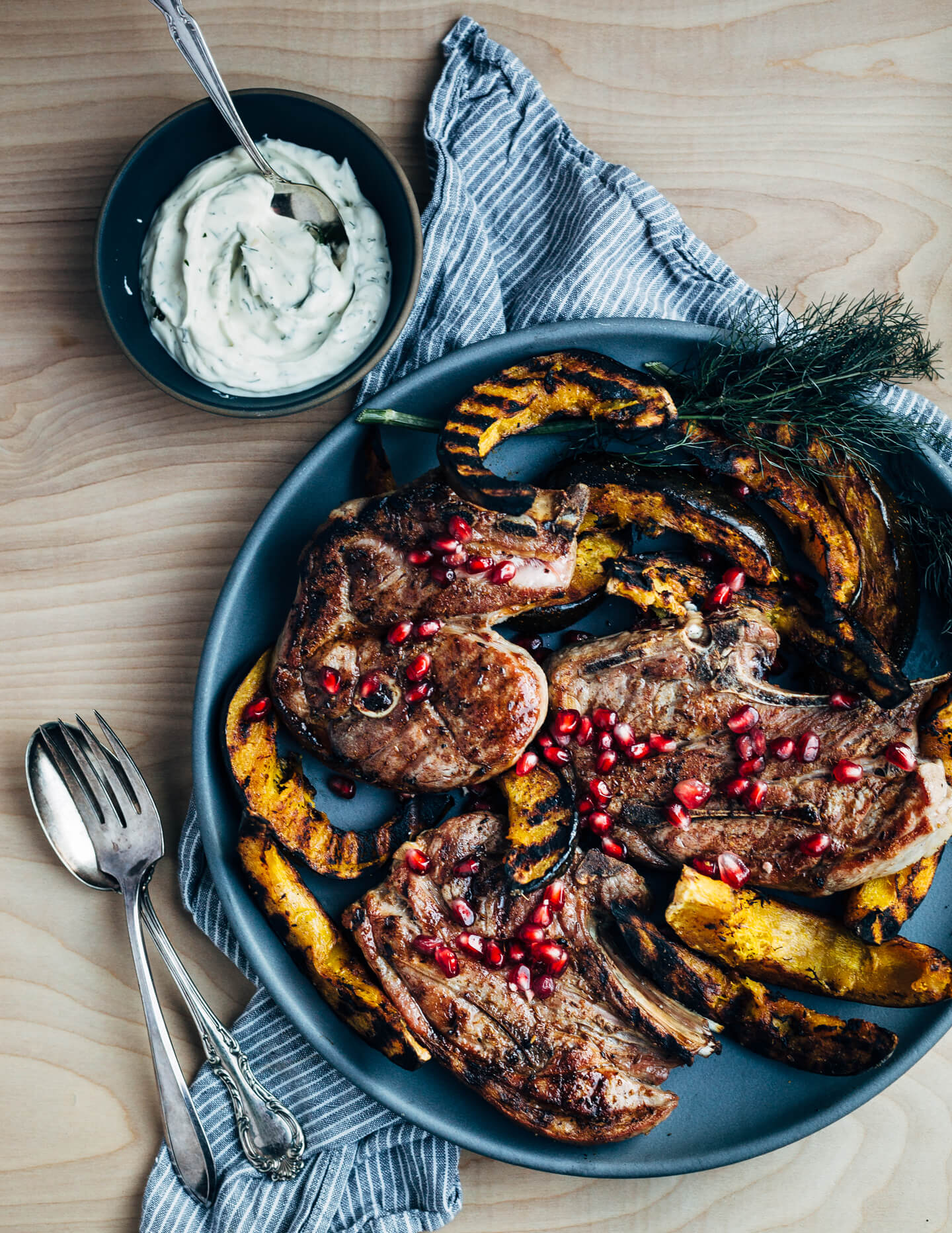 Add a pop of char and smoke to your Thanksgiving feast with this recipe for cumin-rubbed grilled lamb chops, grilled acorn squash wedges, dill and fennel tzatziki, and pomegranate arils. 