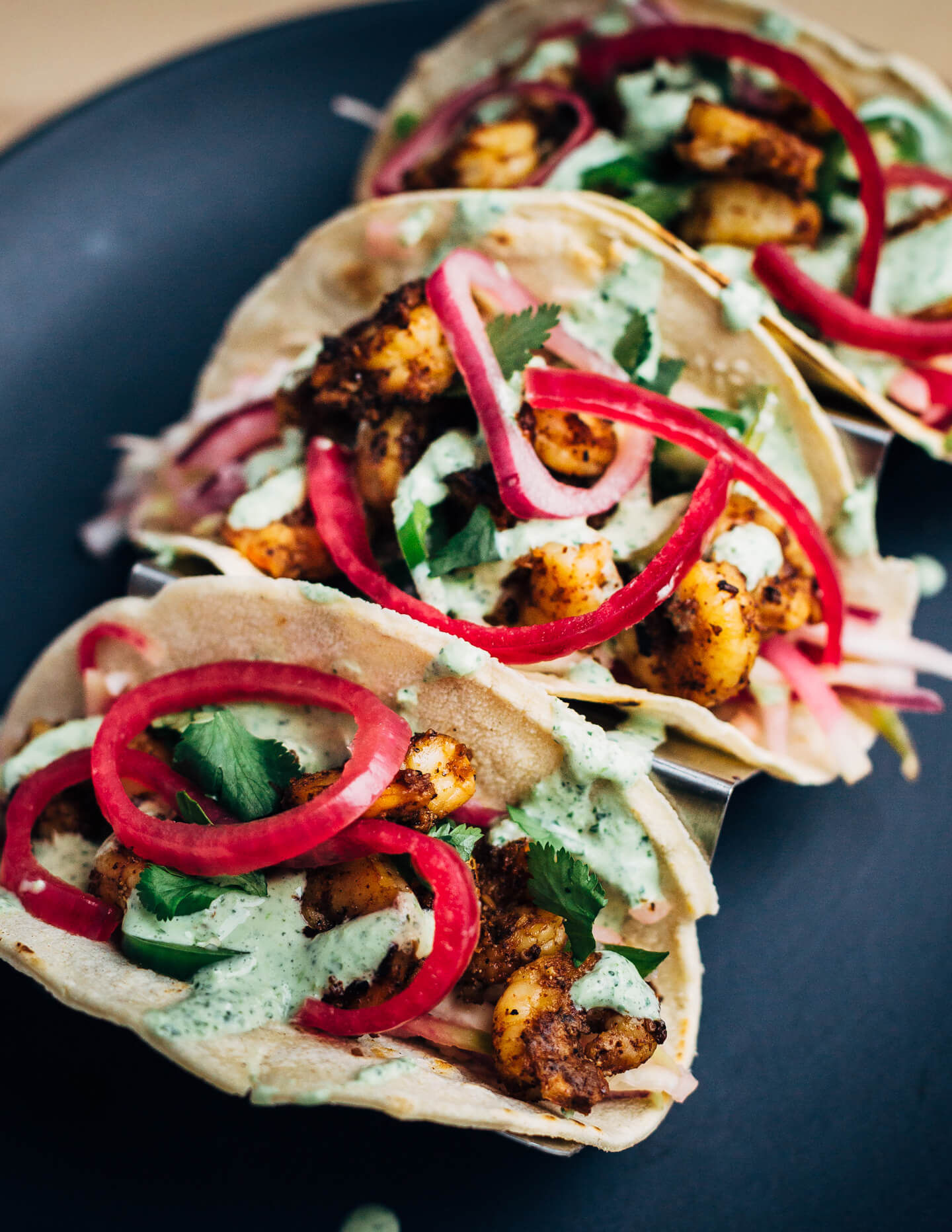 These easy (and delicious!) shrimp tacos feature pan-seared shrimp tossed with lots of chili, cumin, and garlic powder, a simple winter slaw made with watermelon radishes and jicama, and a quick cilantro-yogurt blender sauce. 
