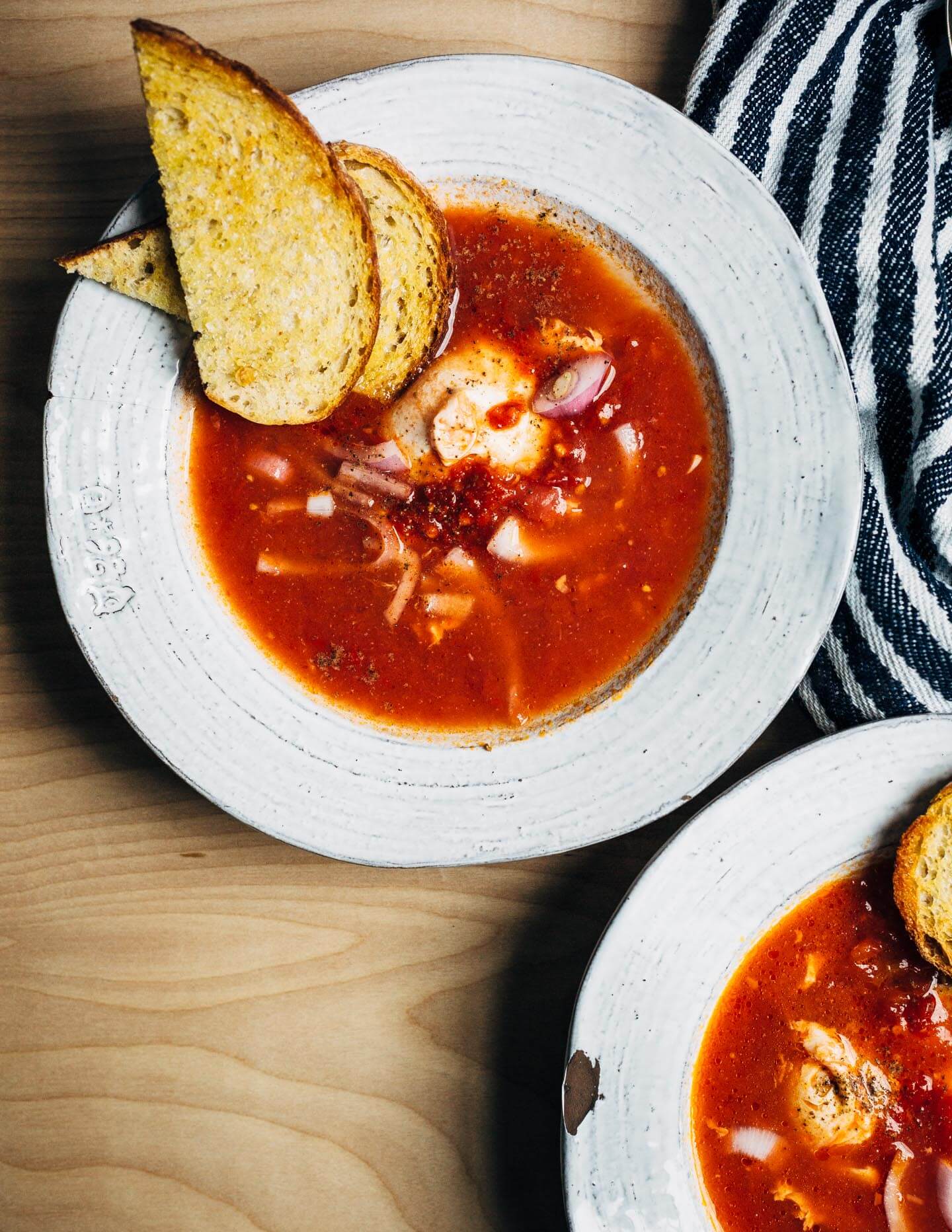 A simple tomato soup with poached eggs that can be as easy or as complex as you'd like. This one has harissa for heat and a little crunch from pickled onions. Golden, garlicky croutons are extra, but so delicious.