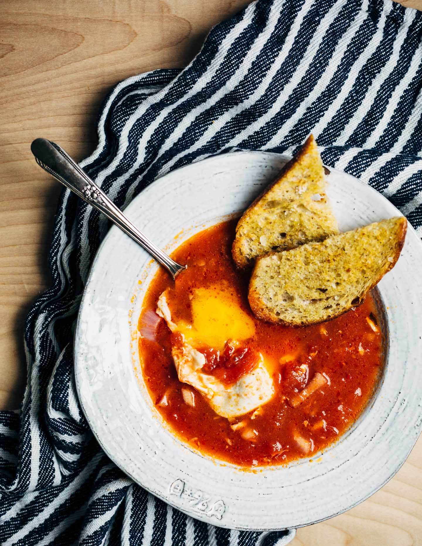 A simple tomato soup with poached eggs that can be as easy or as complex as you'd like. This one has harissa for heat and a little crunch from pickled onions. Golden, garlicky croutons are extra, but so delicious.
