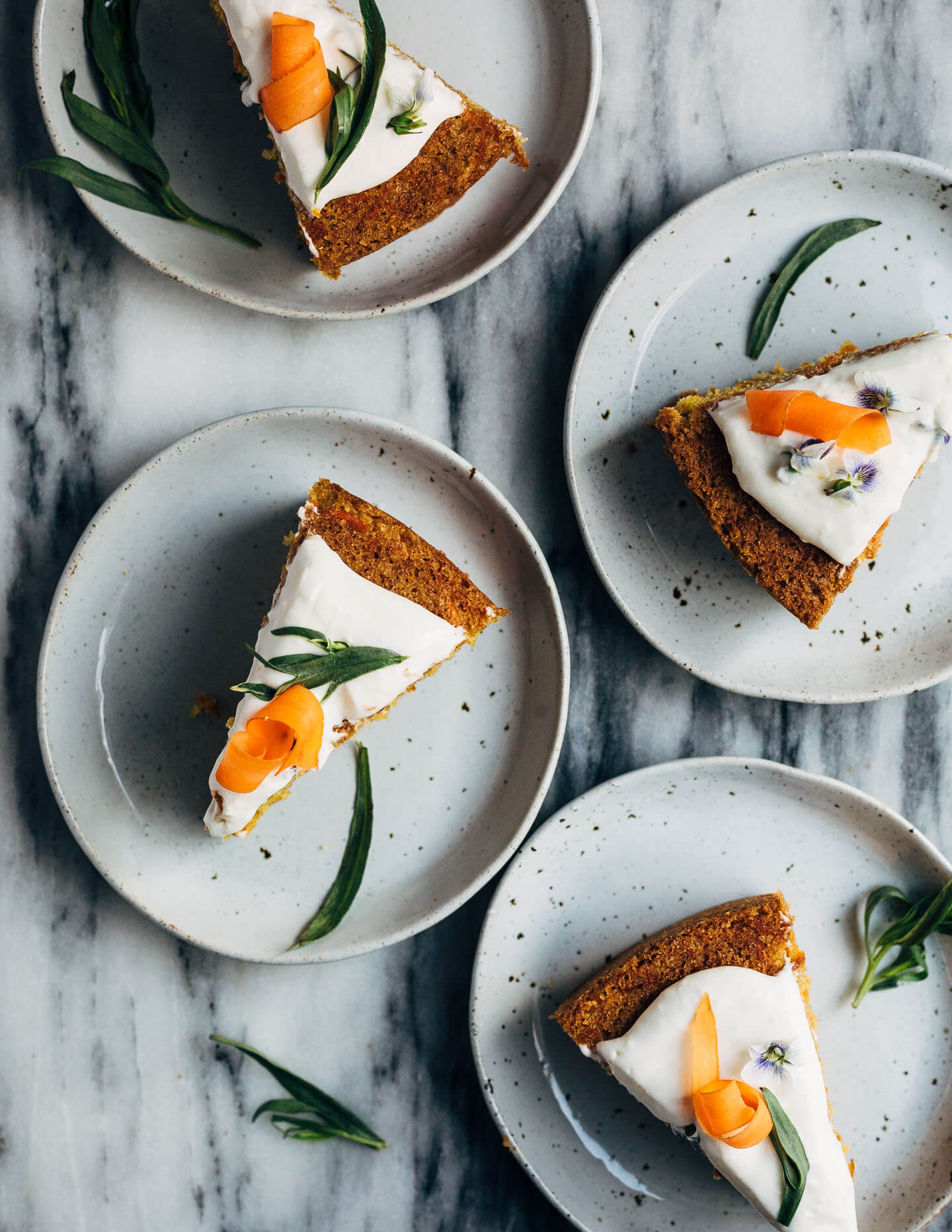 A simple olive oil carrot cake for spring celebrations! The tender, springy whole wheat crumb is suffused with nutty olive oil, fresh carrots, and orange zest. The cake is topped with an airy, lightly sweet yogurt and cream cheese frosting, carrot ribbons, tarragon, and edible flowers. 