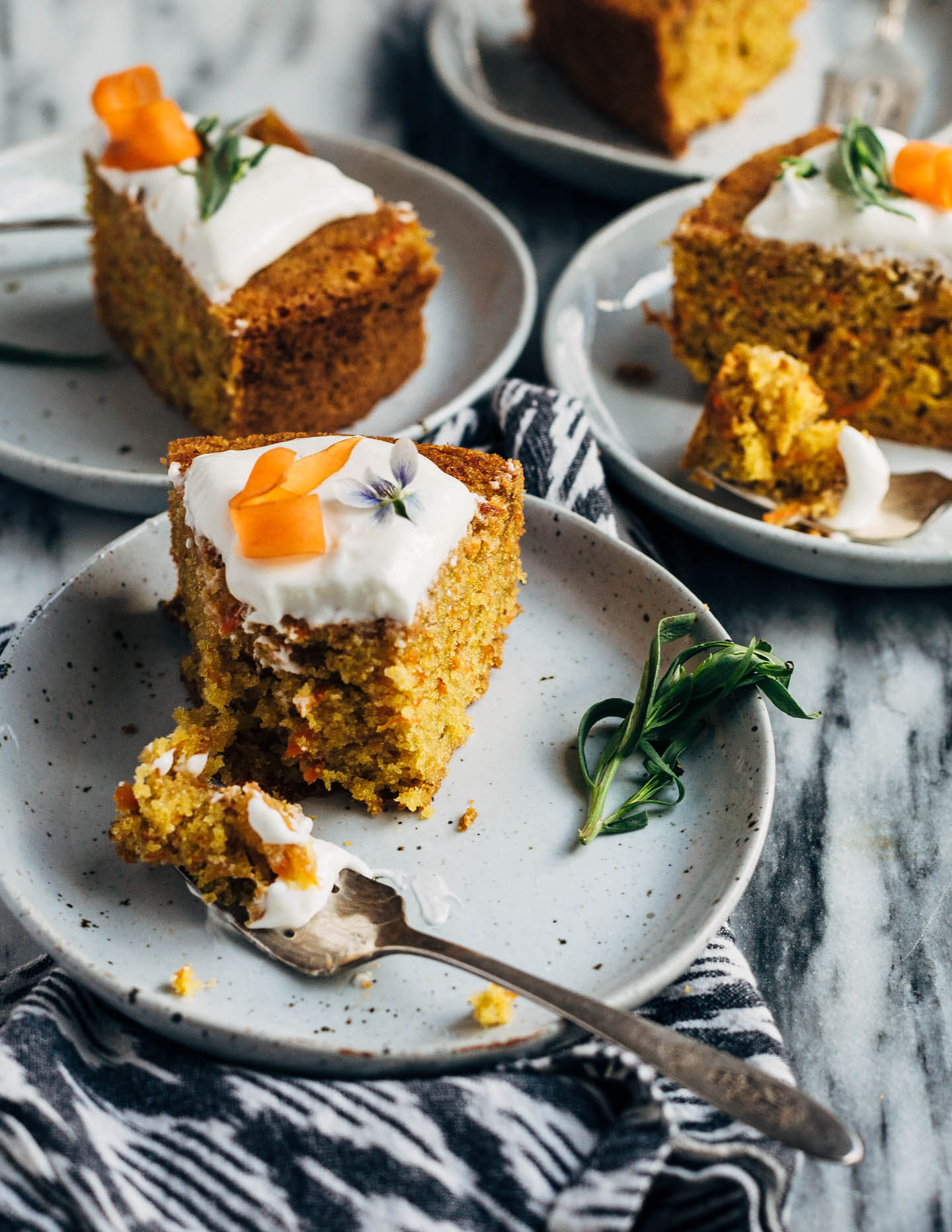 A simple olive oil carrot cake for spring celebrations! The tender, springy whole wheat crumb is suffused with nutty olive oil, fresh carrots, and orange zest. The cake is topped with an airy, lightly sweet yogurt and cream cheese frosting, carrot ribbons, tarragon, and edible flowers. 