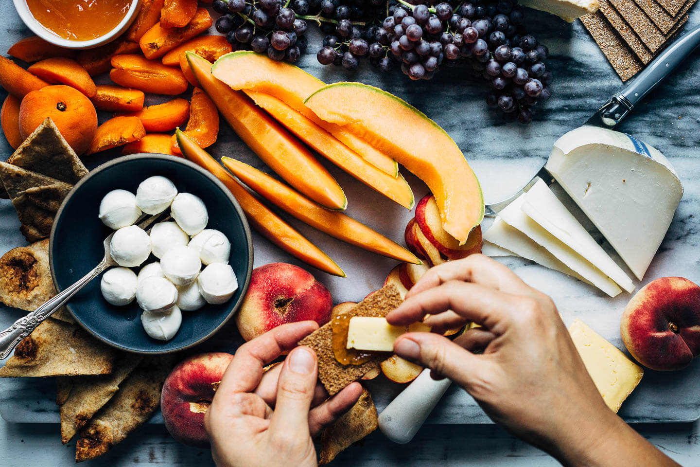 Putting together the perfect bite from a simple summer fruit and cheese board.