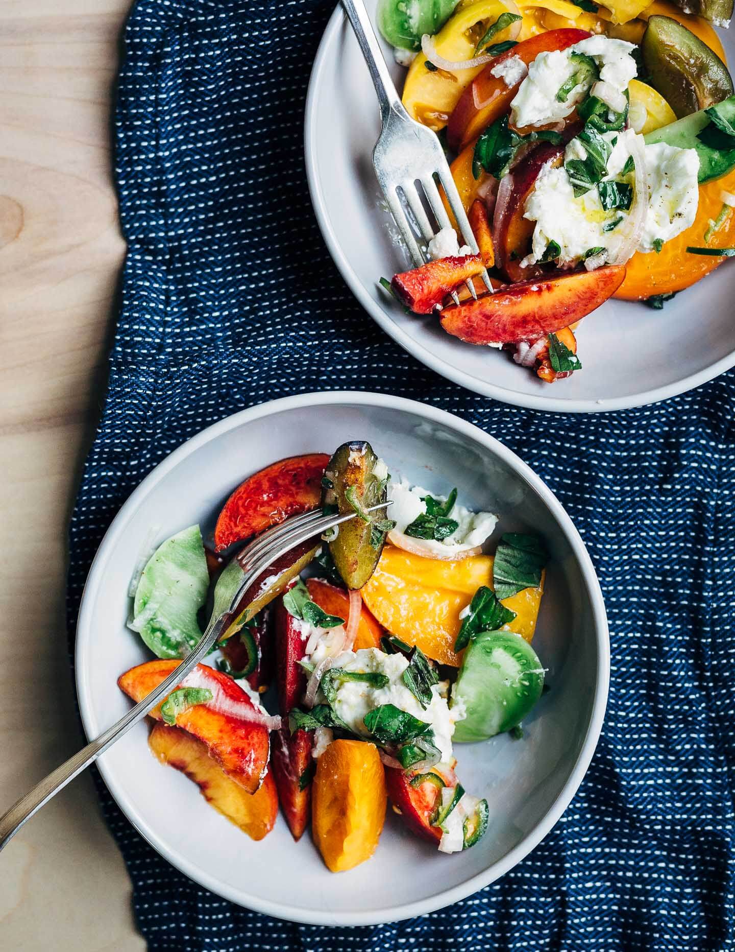 A summery stone fruit and tomato salad in two bowls.