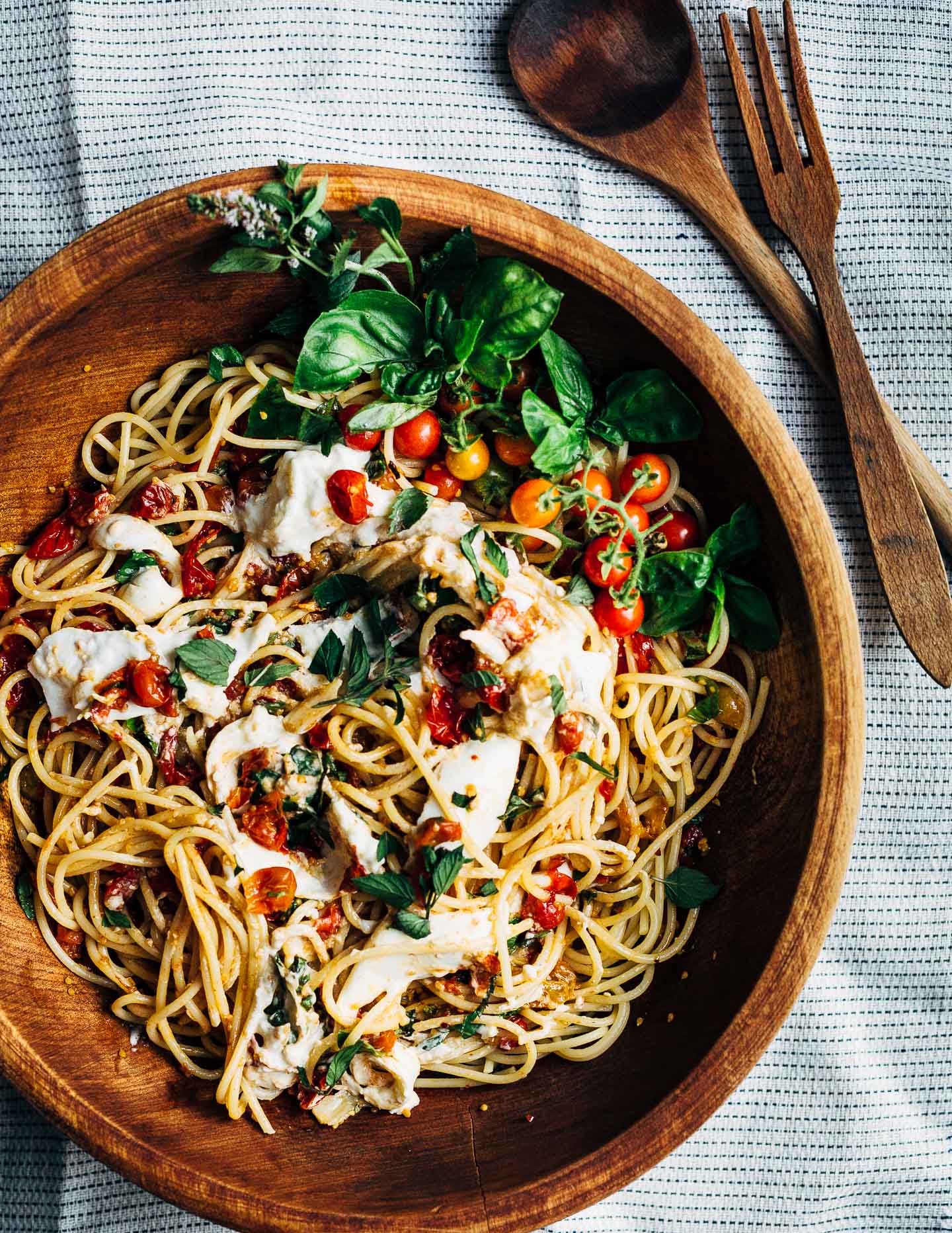 A big wooden bowl filled with al dente spaghetti and roasted tomato cherry marinara made with garden fresh cherry tomatoes.