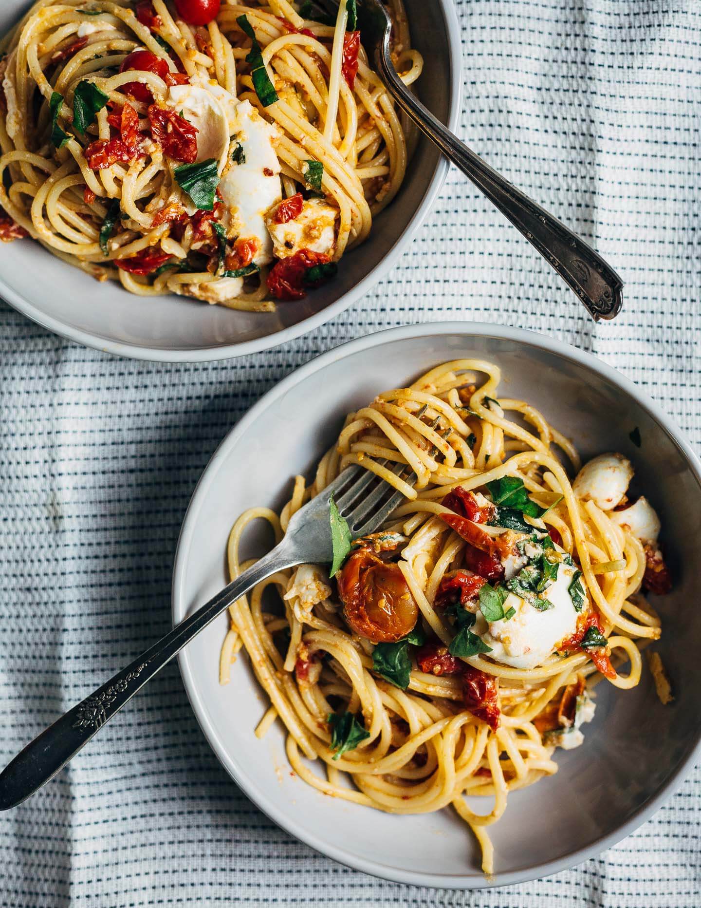 Swirls of al dente spaghetti topped with roasted cherry tomato marinara, burrata, and fresh herbs.