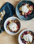 Gluten-free plum crisp topped with a big scoop of vanilla ice cream.
