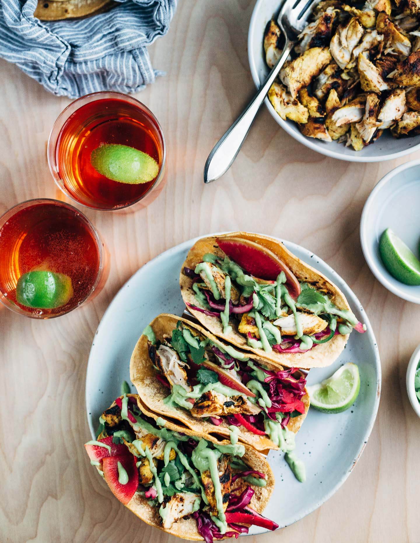These quick and easy grilled chicken tacos start with a vibrant orange and lime juice marinade, and are layered with avocado-lime sauce, and a simple red cabbage and radish slaw.