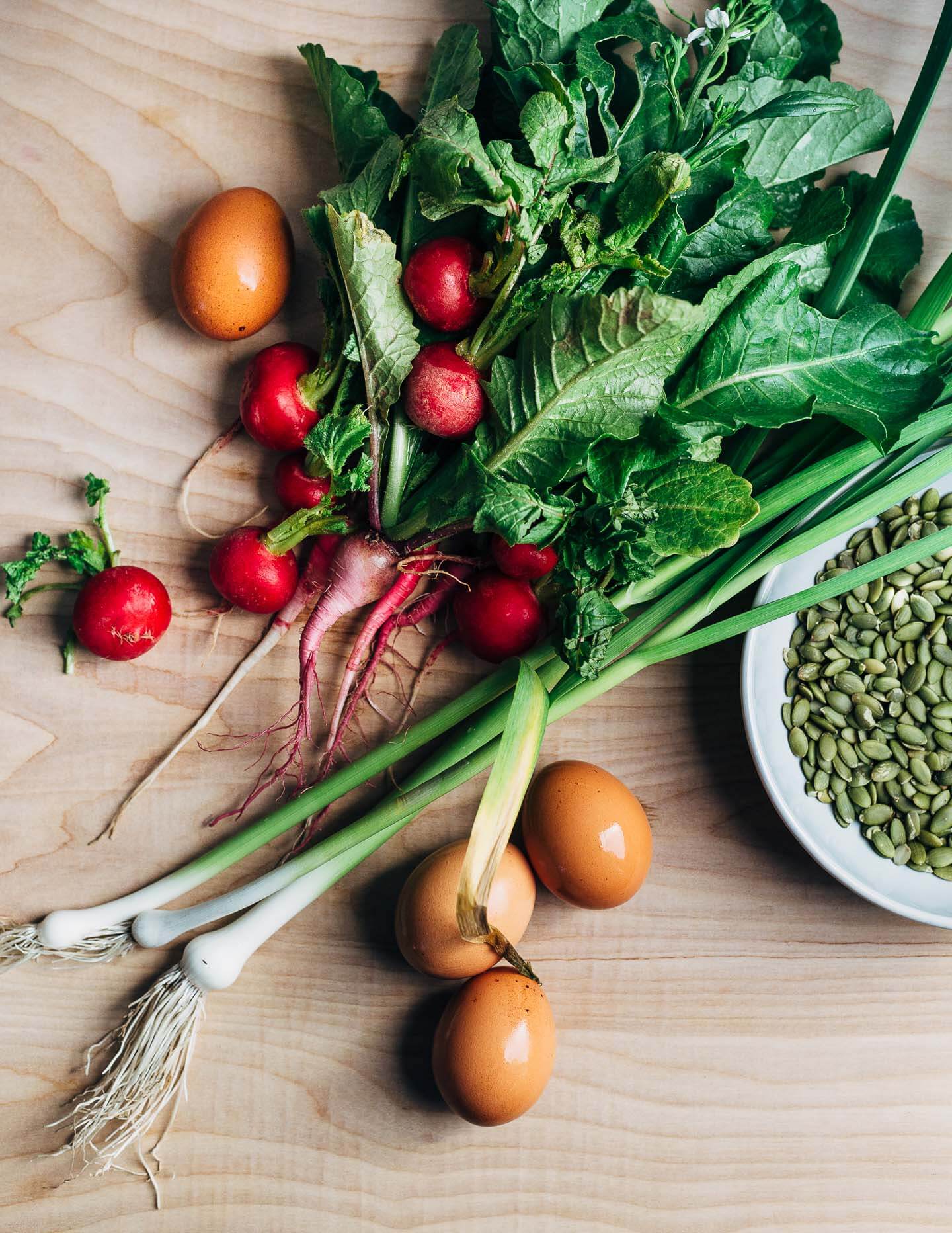 Green garlic stalks, radishes, and eggs.
