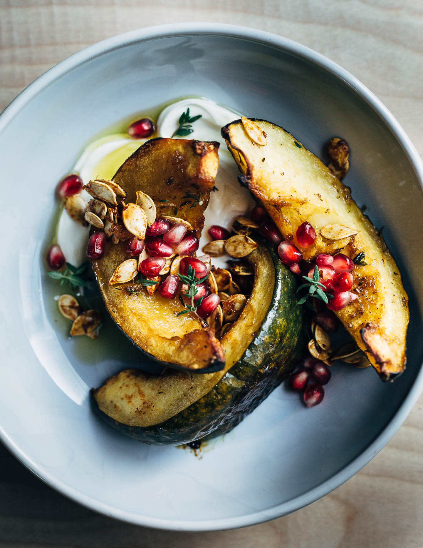 Sweet and savory roasted acorn squash wedges tossed with brown sugar, spicy paprika, black pepper, and fresh thyme. The squash is served with a dollop of crème fraîche, toasted squash seeds, and pomegranate arils.