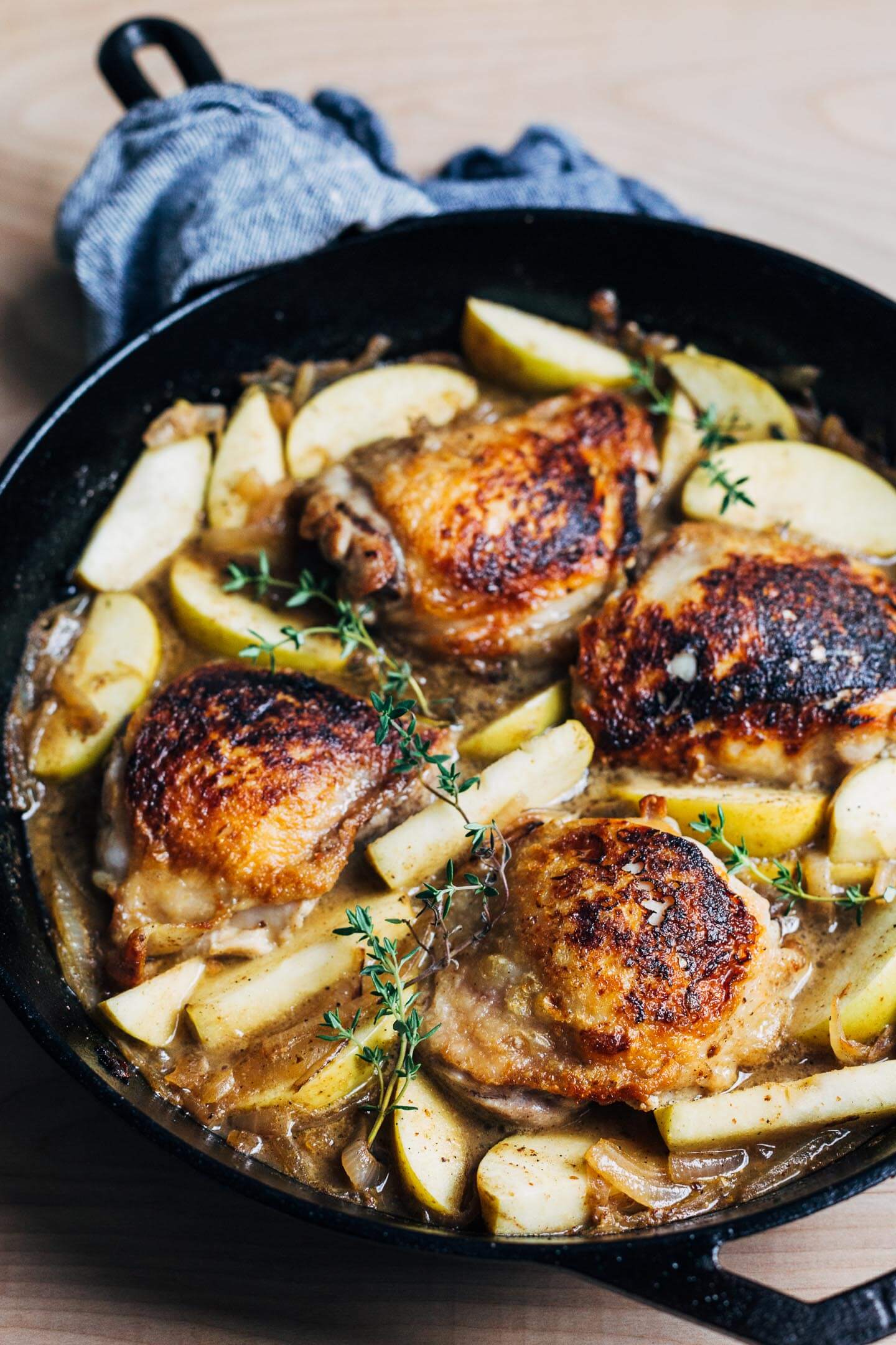 Seared chicken thighs with onions and apples, ready to go into the oven.