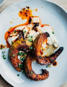 A plate with roasted squash, chili oil, and a dollop of ricotta.