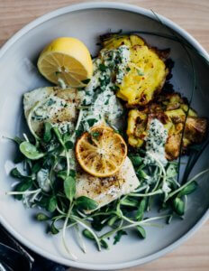 A bowl with smashed potatoes, cod, and sprouts.