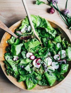 A wooden bowl filled with a green salad