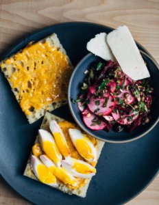 A gray plate with focaccia, feta slices, pimenton aiol, and sliced eggs.