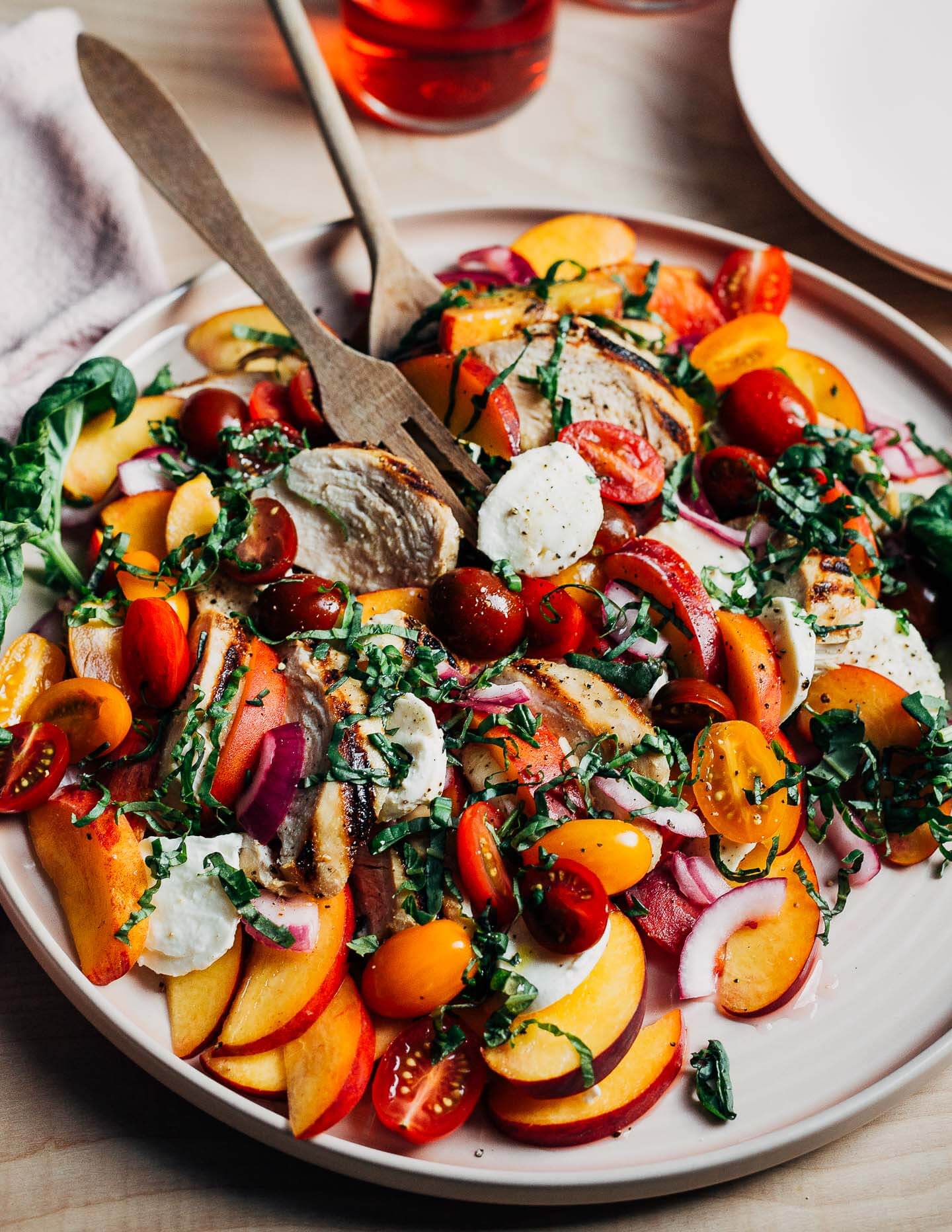 A platter with a peach and grilled chicken caprese salad