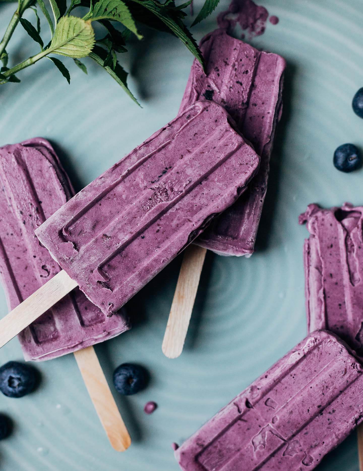 A close up view of purple blueberry popsicles on a plate. 