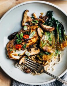 A plate with glazed cod, bok choy, and other vegetables.