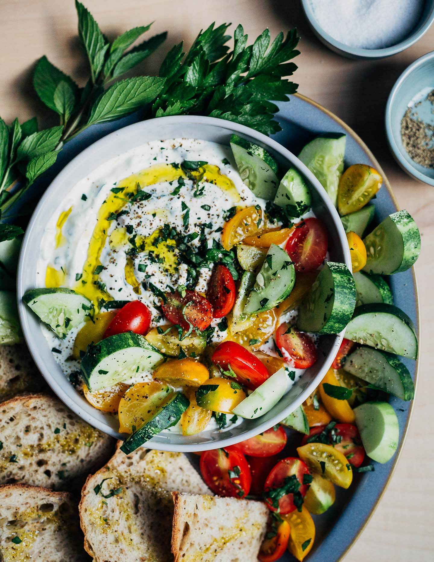 A bowl with dip and vegetables and toast surrounding it. 
