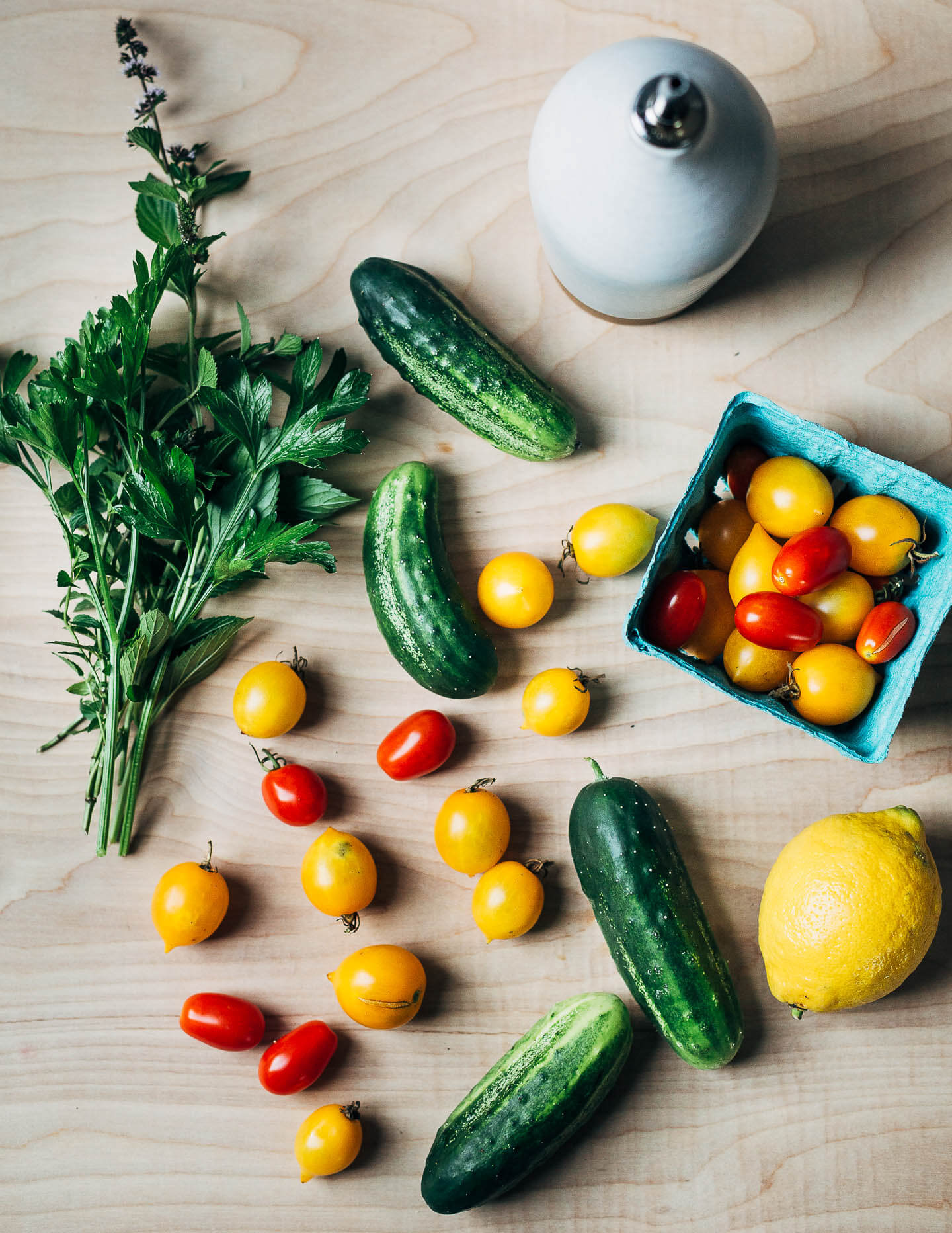 An array of garden vegetables, herbs, and an olive oil dispenser.