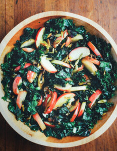 A bowl of kale salad with sautéed apples on top.