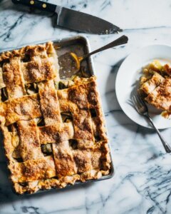 A lattice-top slab pie with one slice removed on a marble table.