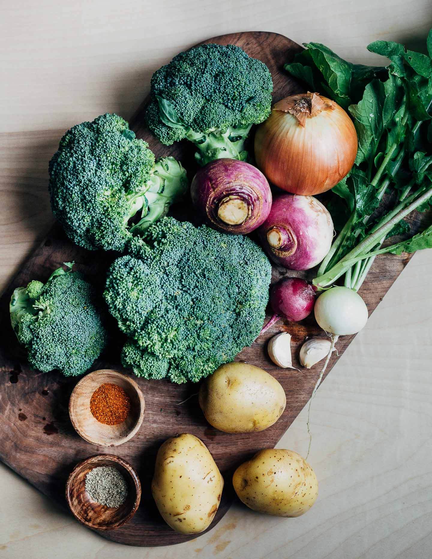 Broccoli and other vegetables arranged on a cutting board. 