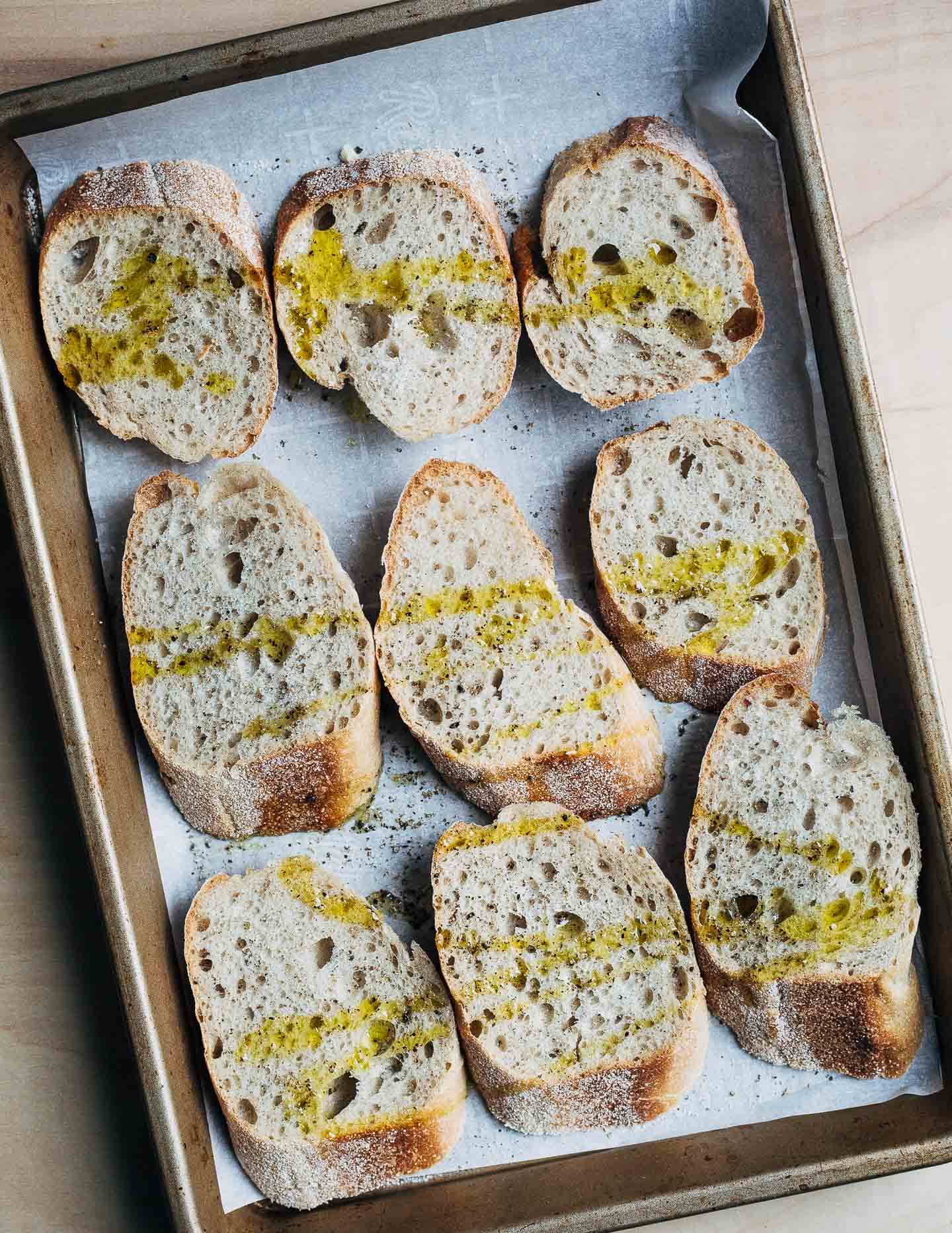 A sheet pan with sliced baguette for croutons.