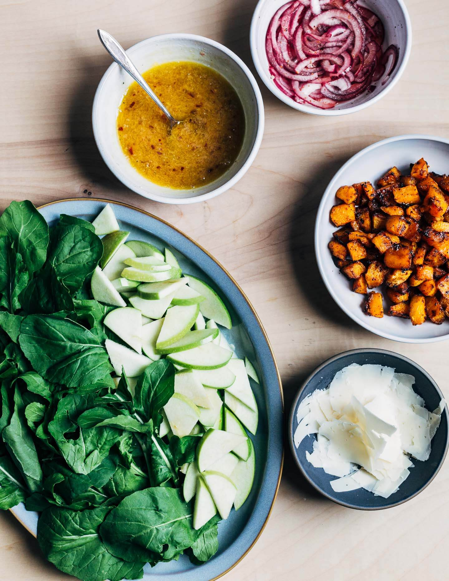 Ingredients for a butternut squash salad arranged in little bowls.