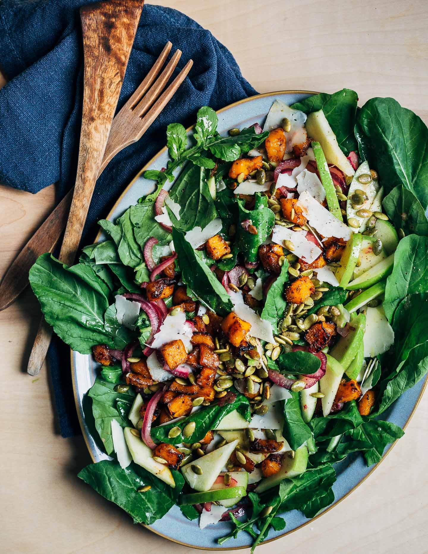 A platter of salad made with squash, pumpkin seeds, apples, and cheese. 