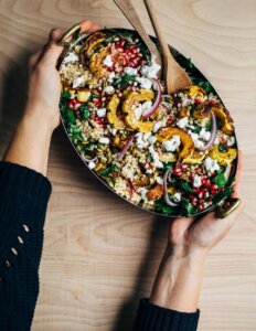 Hands holding a platter of salad.