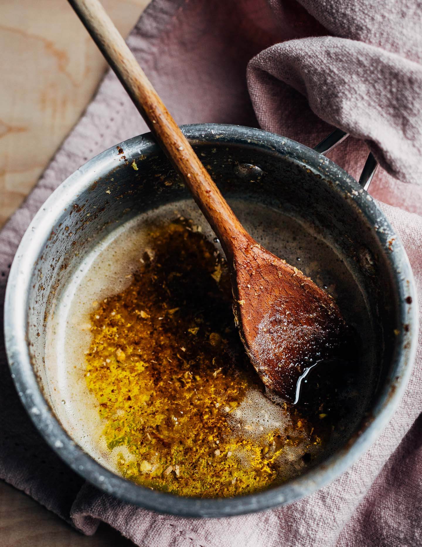 A saucepan of browned butter with flecks of ginger. 