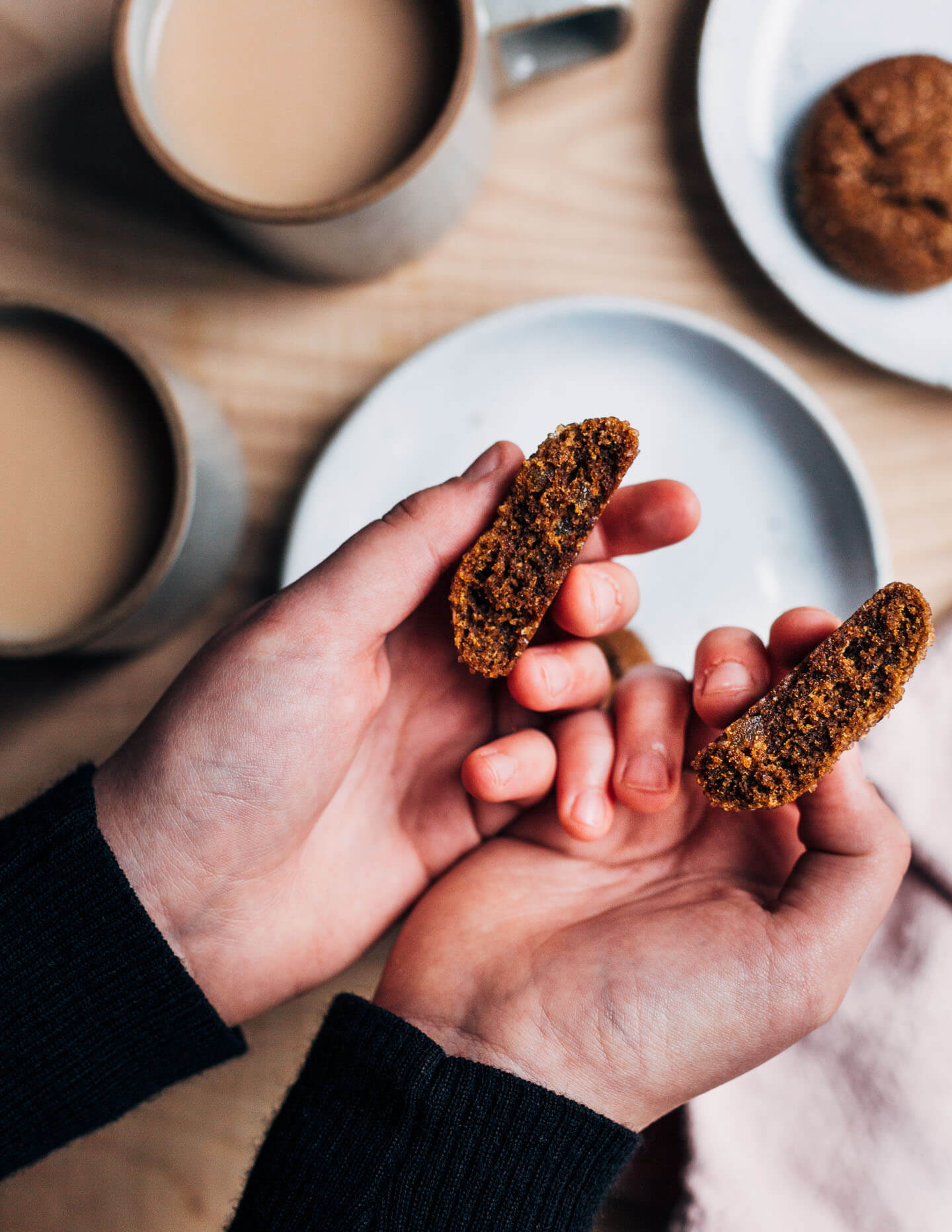 Two hands breaking a cookie apart. 